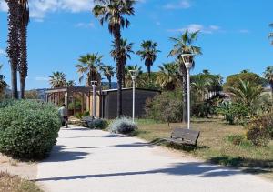 Sunny Cottage في فريجوس: حديقة فيها نخيل ومقعد وجناح