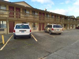 zwei Autos auf einem Parkplatz vor einem Hotel geparkt in der Unterkunft Stagecoach Inn Motel in Molalla