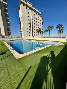 a large swimming pool in front of a tall building at Apartamento acogedor con vistas al Mar Menor MINIMO 2 NOCHES in San Javier