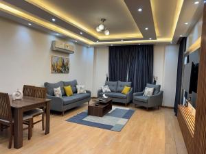 a living room with couches and a table and a tv at Rehab Modern Apartment in New cairo