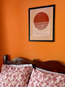 a bedroom with an orange wall with a picture above a bed at Guest House Rosa do Mar in Olinda