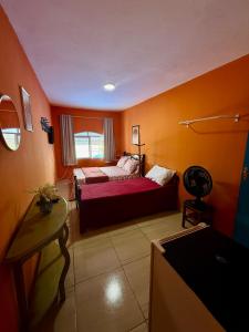 a bedroom with a bed in a room with orange walls at Guest House Rosa do Mar in Olinda