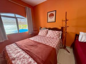 a bedroom with a bed with orange walls and a window at Guest House Rosa do Mar in Olinda