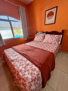a bedroom with a bed with orange walls and a window at Guest House Rosa do Mar in Olinda
