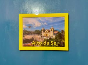 a framed picture of a house on a blue wall at Guest House Rosa do Mar in Olinda