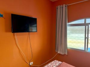 a room with a tv on the wall with a window at Guest House Rosa do Mar in Olinda