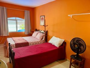 a bedroom with two beds and a fan at Guest House Rosa do Mar in Olinda
