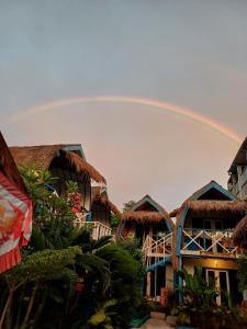 een regenboog in de lucht boven een groep huizen bij Tropical House Bungalows in Gili Trawangan
