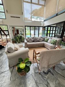a large living room with couches and tables and windows at Rare, Special Beach Pool Villa in Hua Hin