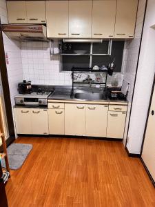 a kitchen with white cabinets and a wooden floor at ZYZSumiyoshichō 2K SJ0254 in Tokyo +3 photos
