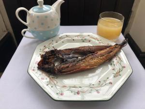 a fish on a plate on a table with a glass of orange juice at Forda Farm Bed & Breakfast in Holsworthy