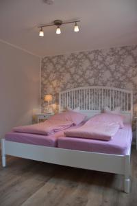 ein Schlafzimmer mit einem weißen Bett mit rosa Kissen in der Unterkunft Bungalow Gartenzauber in Grube