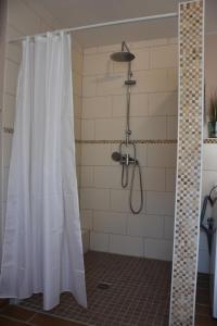 eine Dusche mit einem weißen Duschvorhang im Bad in der Unterkunft Bungalow Gartenzauber in Grube