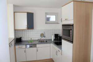 a white kitchen with a sink and a microwave at Ferienwohnung Sünnenkringel 58 in Zingst