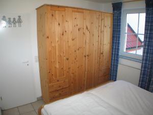 a bedroom with a wooden cabinet next to a bed at Ferienwohnung Sünnenkringel 58 in Zingst +14 photos