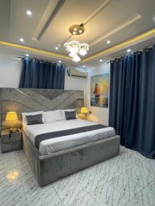 ポートハーコートにあるCZ Hotelのベッドルーム1室(青いカーテン付きの大型ベッド1台付)