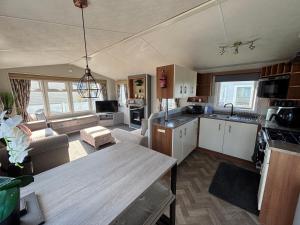 a kitchen and living room with a table in a room at Sunnymede - B8 on Fantasy Island caravan with hot tub, WiFi, pet friendly - Meadow Lakes Caravan & Lodge Hire in Ingoldmells