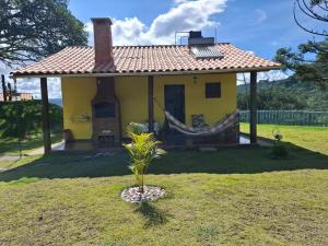 阿尤鲁奥卡Chalé Mirante Da Guapiara的庭院内带吊床的黄色小房子