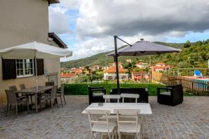 eine Terrasse mit Tischen, Stühlen und Sonnenschirmen in der Unterkunft Martins House Quartos in Arouca