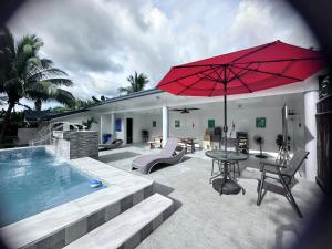 a pool with a table and a red umbrella at Amadeo Verde in Amadeo