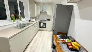 a kitchen with white cabinets and a table with fruit on it at Cozy 5-Bed Caldecott Stays-Sleep 6 in Manchester
