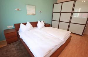 a bedroom with a large bed with white sheets and pillows at Apart 15 by Alpenidyll Apartments in Schladming +2 photos