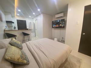 une chambre avec un lit avec une télévision au mur dans l'établissement Llames Studios Near Mactan Airport - Rustic & Spacious, à Lapu Lapu City