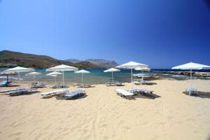 a beach with white umbrellas and chairs and the ocean at Nautilus Bay Hotel in Kissamos