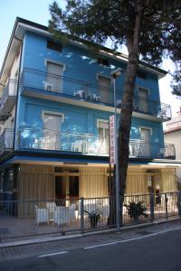 un edificio blu con un albero di fronte di Hotel Orchidea a Rimini