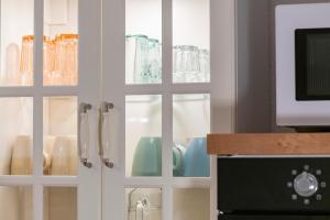 un armadietto bianco con porte in vetro e stoviglie di MarEwa Ferien a Mechernich