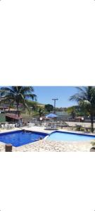 ein Bild eines Swimmingpools mit Palmen in der Unterkunft Condomínio Marina Clube in São Pedro da Aldeia