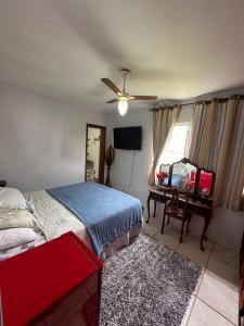Schlafzimmer mit einem Bett, einem Deckenventilator und einem Schreibtisch in der Unterkunft Condomínio Marina Clube in São Pedro da Aldeia