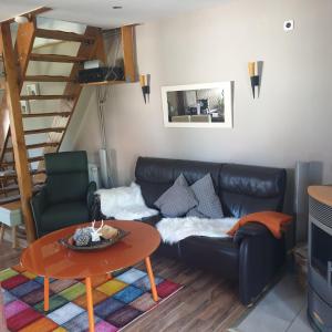 a living room with a black leather couch and a table at Feha ehemaliger Stall in Langelsheim