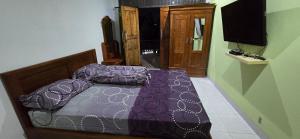 a bedroom with a purple bed and a television at Devina House in Kuta