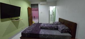 a bedroom with a bed and a flat screen tv at Devina House in Kuta