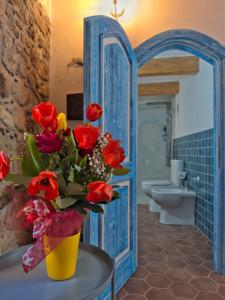 a bathroom with a yellow vase with red flowers in it at Regnos Altos boutique rooms in Bosa +63 photos