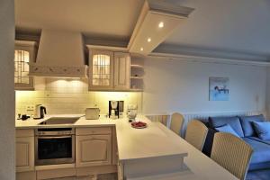 a kitchen with white cabinets and a table with chairs at Hanseat II Whg 145 in Grömitz +10 photos