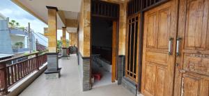 Un porche con puerta de madera y balcón. en Devina House, en Kuta