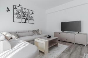 a white living room with a couch and a tv at Cream Divine in Oradea +19 photos