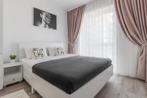 a white bedroom with a large bed and a window at Cream Divine in Oradea