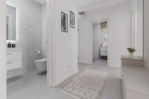 a white bathroom with a toilet and a rug at Cream Divine in Oradea