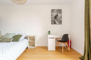 Un dormitorio con una cama, un escritorio y una silla. en Le Briand - Centre Ville - Calme - Terrasse, en Saint-Nazaire