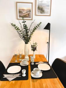 a table with plates and cups and a vase on it at Ferienwohnung Stamer in Eckernförde