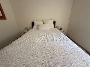 Una cama blanca grande con dos almohadas encima. en הבית של אסף - 3 וילות משפחתיות זהות, en H̱osen