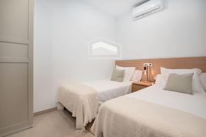 a bedroom with two beds with white sheets at ElsPeixets Home Mallorca - ArtHouse in Colonia Sant Jordi