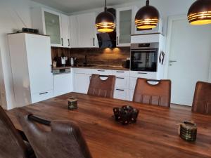 a kitchen with a wooden table and a kitchen with white cabinets at Seehaus Westufer in Walchum