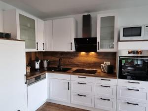 a white kitchen with white cabinets and a sink at Seehaus Westufer in Walchum