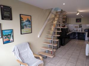a living room with a spiral staircase and a chair at L'Escale VICHY in Vichy