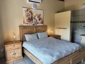 a bedroom with a bed and a painting on the wall at Le Lion Dort in Marloth Park