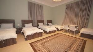 a room with three beds and a table and a rug at Madina House in Al-Salam